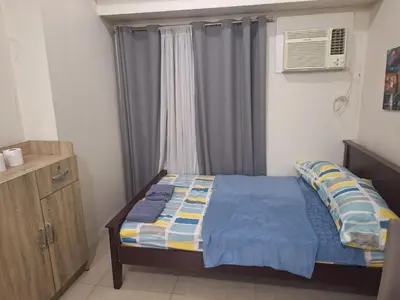 a small bedroom with a bed and a window at Chelsea Suites at the Beacon Makati in Manila