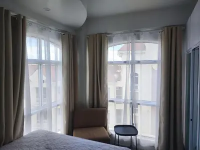a bedroom with a bed and a chair and windows at Two Bedroom - Presidio Lakefront in Manila