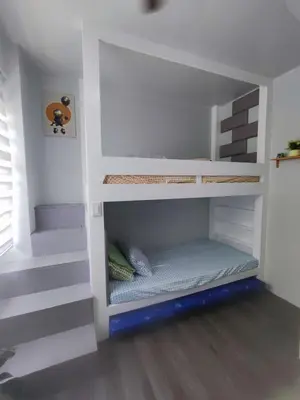 a white bunk bed with stairs in a room at Two Bedroom - Presidio Lakefront in Manila