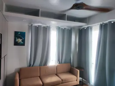 a couch in a living room with blue curtains at Two Bedroom - Presidio Lakefront in Manila