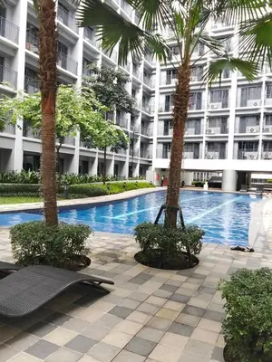 a swimming pool with two palm trees in front of a building at Shore2 tower2 in Manila