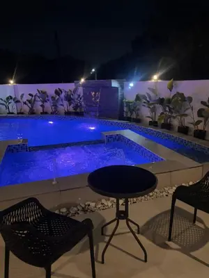 a table and chairs in front of a swimming pool at night at Villa Serene Resort in General Trias
