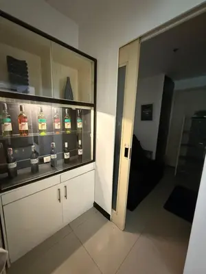 a room with a display case with bottles of alcohol at Staycation By Abby Tower E in Manila