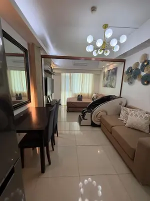 a living room with a couch and a table and a bed at Staycation By Abby Tower E in Manila