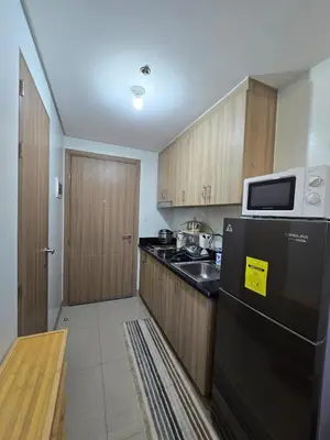 a kitchen with wooden cabinets and a black refrigerator at Chic Urban Retreat near mall of asia in Manila
