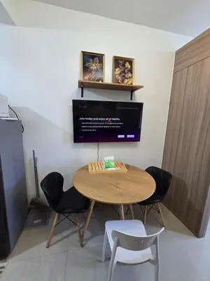 a table in a room with chairs and a tv at Chic Urban Retreat near mall of asia in Manila