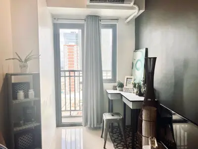 a room with a desk and a large window at Ortigas Business District Residences in Manila