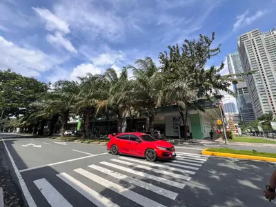 a red car parked on a street with a crosswalk at Ortigas Business District Prime Accommodations in Manila