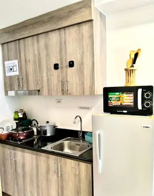 a kitchen with a sink and a refrigerator at Ortigas Business District Prime Accommodations in Manila