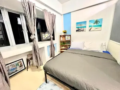 a bedroom with a bed in a room with windows at BGC Mckinley City Center Apartments in Manila