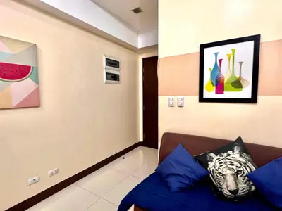a living room with a couch and paintings on the wall at BGC Mckinley City Center Apartments in Manila