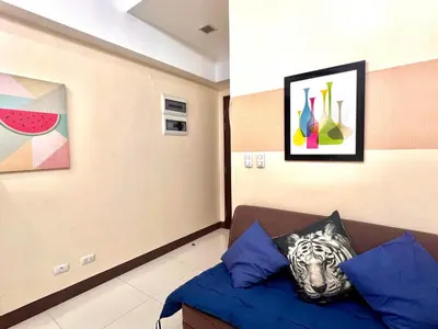 a room with a couch and paintings on the wall at BGC Mckinley City Center Apartments in Manila