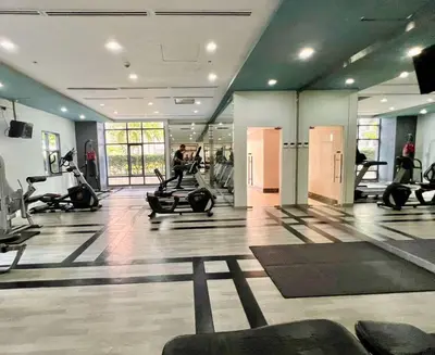 a gym with people exercising on machines in a room at BGC Mckinley City Center Apartments in Manila