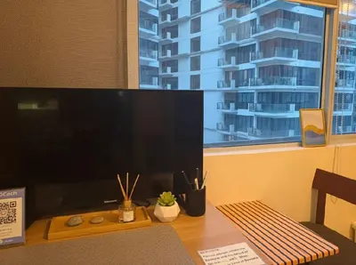 a computer monitor sitting on a desk in front of a window at BGC Mckinley Center Prime Accommodations in Manila