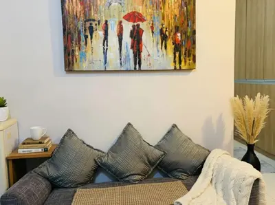 a couch in a living room with a painting on the wall at BGC Mckinley Center Prime Accommodations in Manila