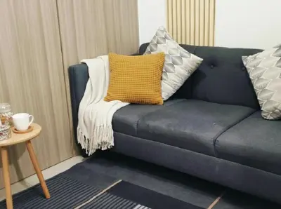 a blue couch with a yellow pillow and a table at Mall Of Asia - Aseana Prime Accommodations in Manila