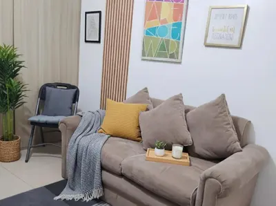 a living room with a brown couch with yellow pillows at Mall Of Asia - Aseana Prime Accommodations in Manila