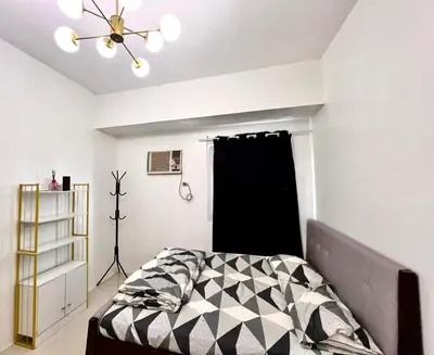 a bedroom with a bed with a black and white comforter at Makati Business District Residences in Manila