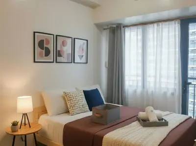 a bedroom with a large bed with a window at Makati Business District Prime Accommodations in Manila