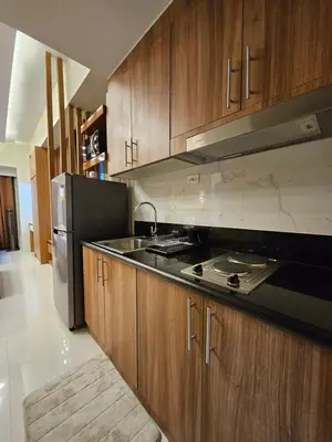 a kitchen with wooden cabinets and a stainless steel refrigerator at Modern Condotel 2Beds near MOA in Manila