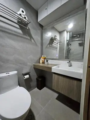 a bathroom with a toilet and a sink and a mirror at Modern Condotel 2Beds near MOA in Manila