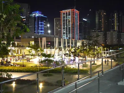 a city at night with people walking down a street at BGC Suites EDSA Makati in Manila