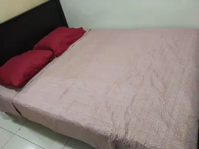 a bed with a pink blanket and two red pillows at Mall Of Asia Sea Condotel in Manila
