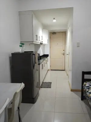 a kitchen with a black refrigerator and white cabinets at Mall Of Asia Sea Condotel in Manila