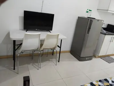 a table with two chairs and a tv and a refrigerator at Mall Of Asia Sea Condotel in Manila