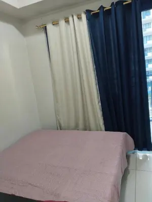 a bedroom with a bed with a blue curtain at Mall Of Asia Sea Condotel in Manila