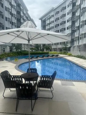 a table and chairs under an umbrella next to a pool at Leaf Residences Alabang Muntinlupa Condotel in Manila