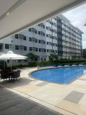 a swimming pool in front of a large building at Leaf Residences Alabang Muntinlupa Condotel in Manila