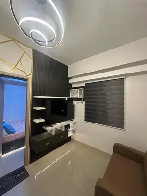 a living room with a couch and a television and a window at Leaf Residences Alabang Muntinlupa Condotel in Manila
