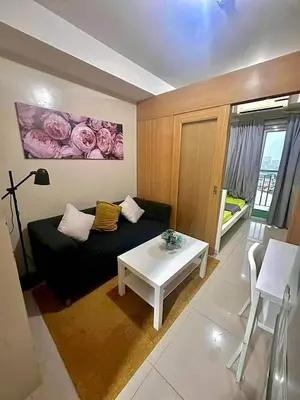 a living room with a black couch and a table at Shell Residence Mall of Asia in Manila
