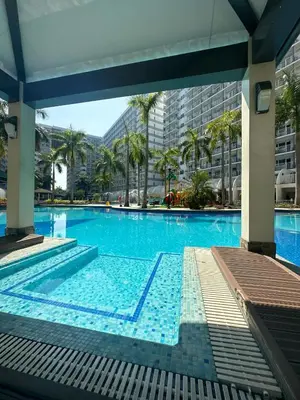 a large swimming pool with palm trees and buildings at Shell Residence Mall of Asia in Manila