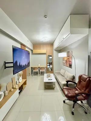 a living room with a couch and a tv on a wall at Comfy Cozy Staycation in Manila