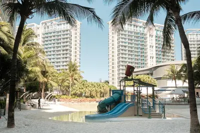 a playground in a park with palm trees and buildings at Bahamas Tower Azure Urban Resort Residences by Nestled Nook in Manila