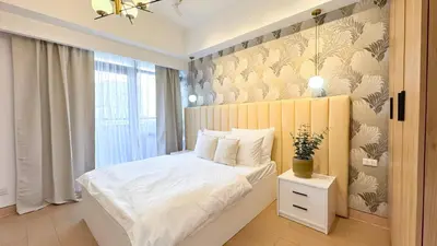 a bedroom with a white bed with a wooden headboard at CYLOS PLACE Manhattan Araneta Center 2BR with BALCONY in Manila