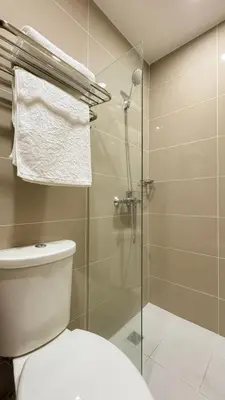 a bathroom with a toilet and a glass shower at CYLOS PLACE Manhattan Araneta Center 2BR with BALCONY in Manila
