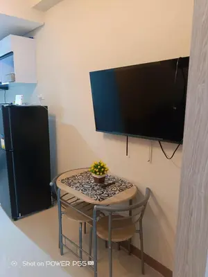 a small table with a chair and a television on a wall at SMDC Field REsidences condo unit in Manila