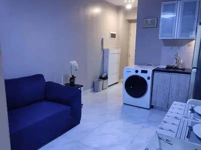 a living room with a blue couch and a washing machine at BP1043 Pool View Staycation Paranaque Pasay in Manila