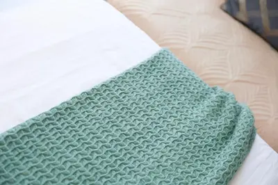 a green and white blanket on a bed at Manhattan Heights Modern Studio in Manila