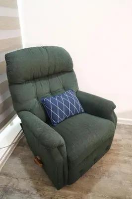 a green chair with a blue pillow in a room at Home Away From Home in Manila