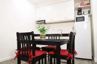 a kitchen with a black table with chairs and a refrigerator at Home Away From Home in Manila