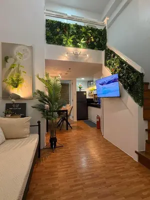a living room with a staircase with plants on the walls at Trendy 3BR Loft Condo along EDSA in Manila