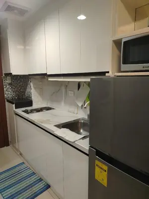a kitchen with white cabinets and a stainless steel refrigerator at Shell Residence by Jas O in Manila