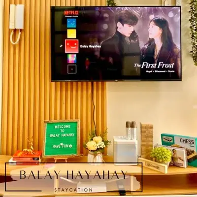 a television on a wall above a shelf with a shelf at Balay Hayahay Staycation in Manila