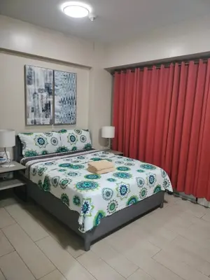 a bedroom with a bed and red curtains at Kylie and Drew Room Near Airport in Manila