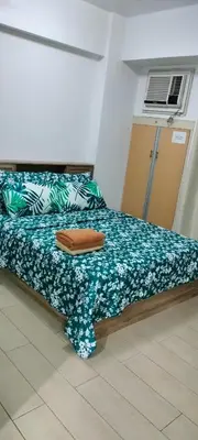 a bedroom with a bed with a green and white blanket at Kylie and Drew Room Near Airport in Manila