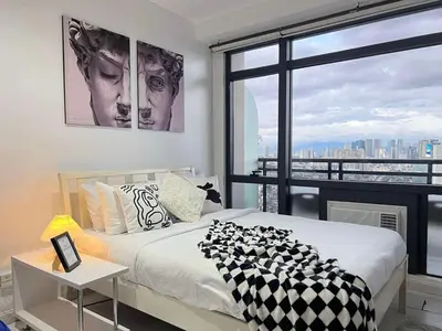 a bedroom with a bed and a large window at Affordable Suite at Gramercy Makati with Balcony & Parking in Manila
